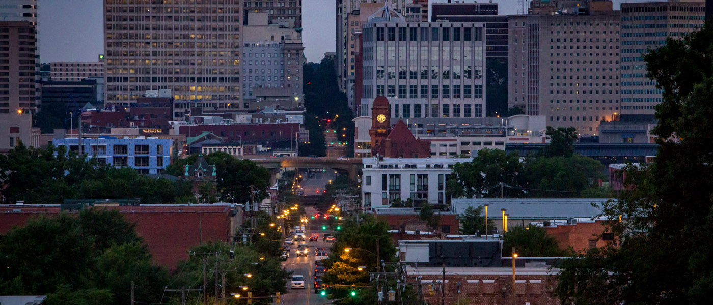 Cars drive down a city street at night